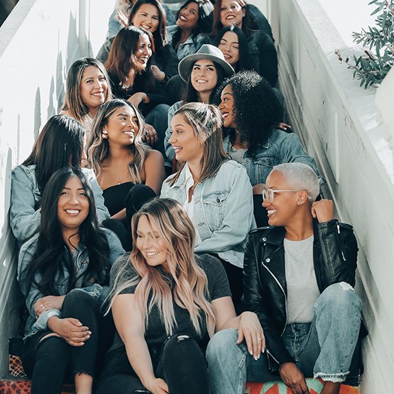 Large group of women laughing and having fun sitting on stairs